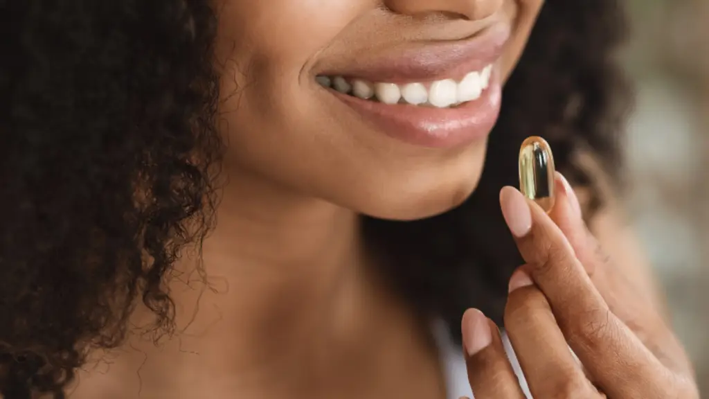 A imagem mostra uma mulher tomando uma cápsula de suplemento alimentar para manter boa saúde. Ela está com o semblante feliz.